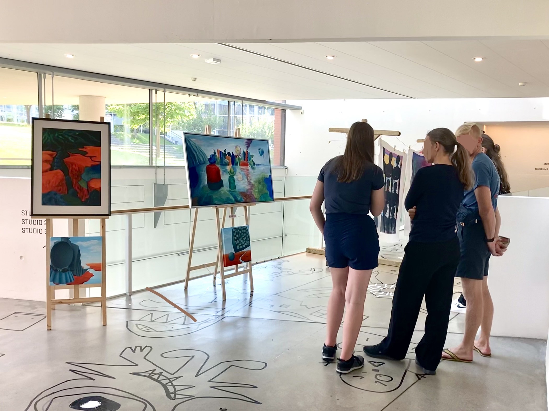 Billede fra Marie Juhls udstilling på ARoS.Tre personer betragter Marie Juhls surrealistiske univers.