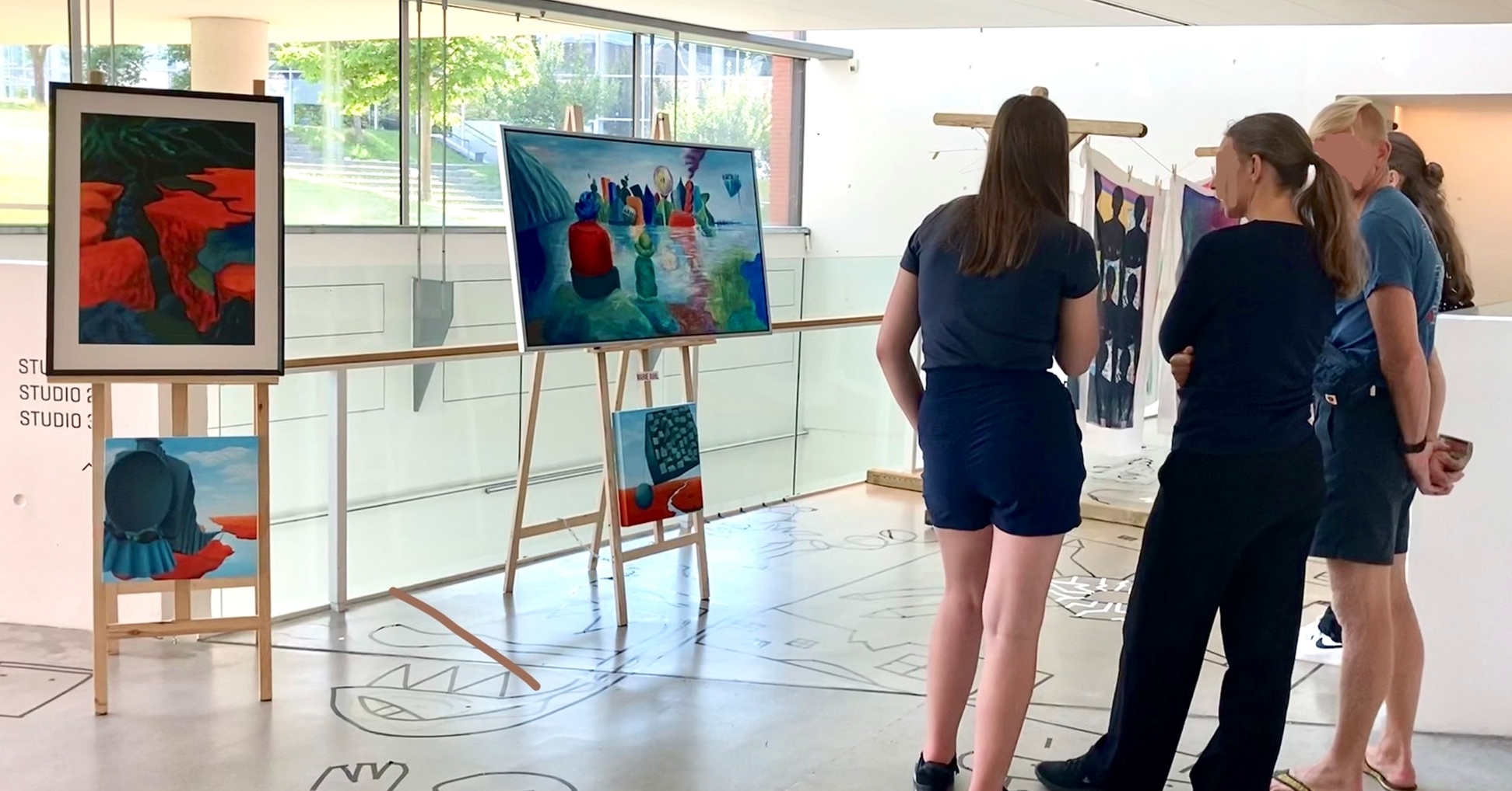 Billede af folk der beundrer Marie Juhls malerier på udstilling.