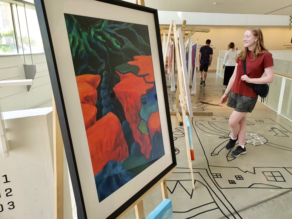 Billede tæt på et af Marie Juhls udstillede værker. Marie Juhl selv ses i højre side af billedet.