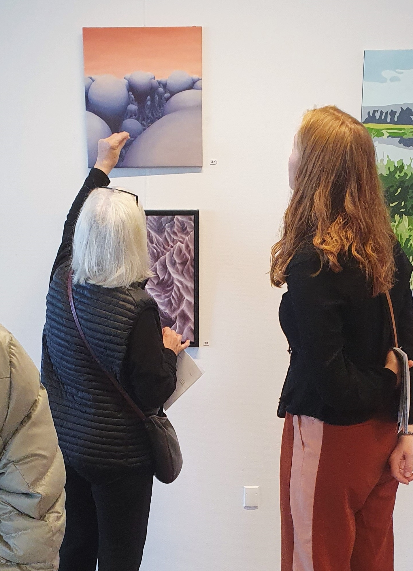 Marie Juhl snakker med nysgerrig kvinde om sine malerier.